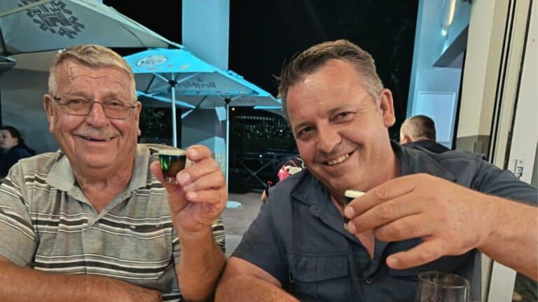 A celebratory moment for the master breeders behind Fourie Forte Lofts, Jaco Fourie and his partner raising a glass to toast their monumental racing pigeon victories. Their elite strain of Fourie Forte Lofts Pigeons continues to dominate prestigious South African events like the Marlbank OLR, showcasing the true joy, friendship, and triumphant spirit of modern pigeon racing at its highest level.