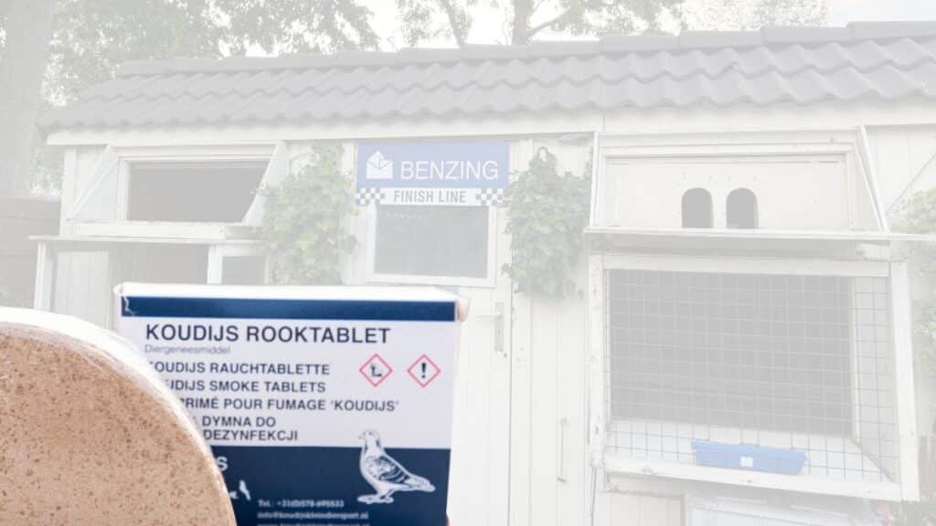 A close up view from the file KoudIjs RookTablet.jpg showing the packaging of Koudijs Smoke Tablets held up outdoors. The box prominently displays the product name in multiple languages alongside an illustration of a racing pigeon. The bright background features a well maintained white wooden pigeon loft with a blue Benzing Finish Line sign mounted above the entrance door.