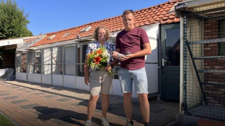 Gerben de Boeij of Combinatie de Boeij & Zoon holds a racing pigeon alongside his mother, Christianne, who holds a celebratory bouquet of flowers. They are standing outside their extensive, modern pigeon loft in Vogelwaarde following their spectacular victory from Toury.