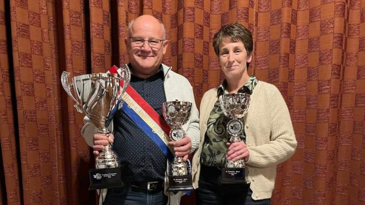 Champion pigeon fancier Huub Hermans and his wife proudly holding their championship trophies and sash for Afdeling Limburg