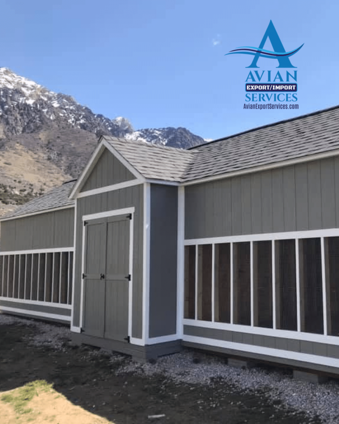 Avian Export Services pigeon holding and quarantine facility with mountain scenery in the background and the company logo visible above the building.