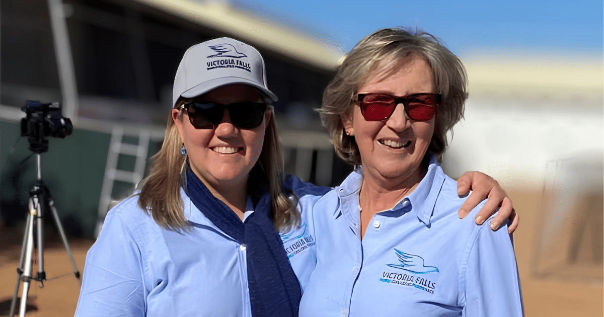 One Loft Races 2 Two smiling representatives of the Victoria Falls World Challenge Pigeon Race management team wearing official branded apparel at the loft site.