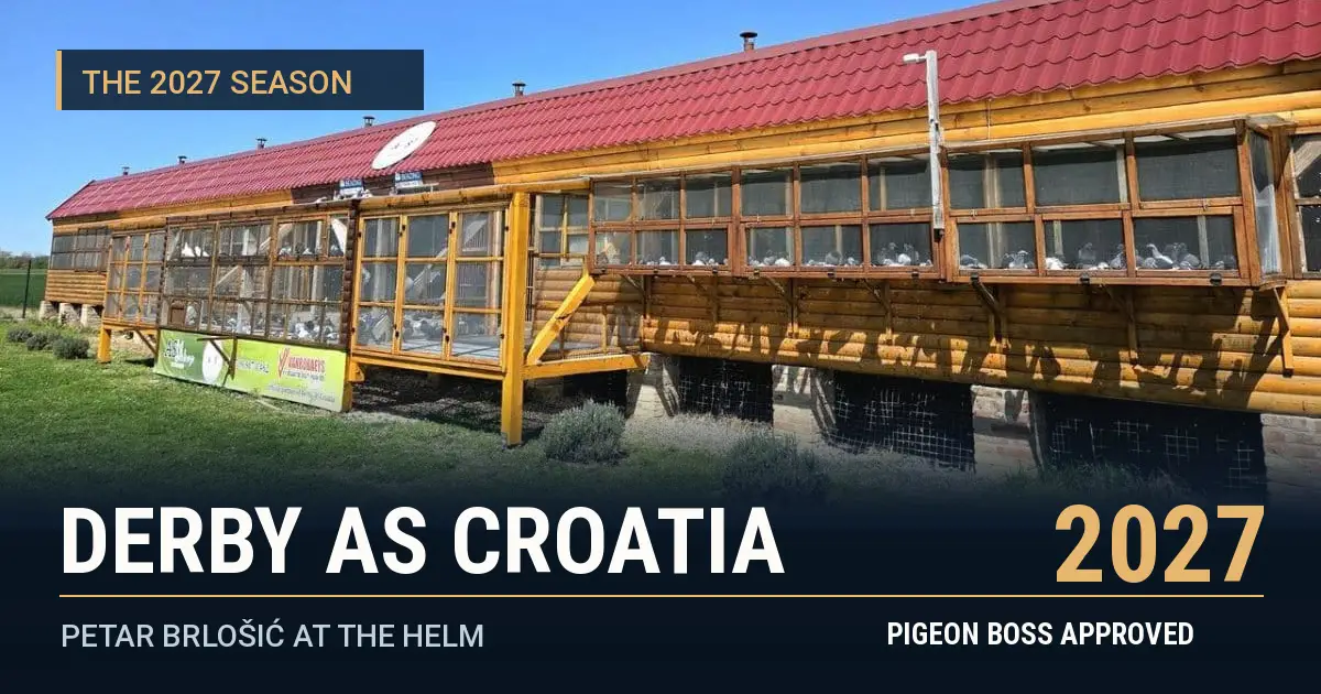 Long wooden Derby AS Croatia racing pigeon loft with red roof and front aviaries beside a green grassy area under blue skies.