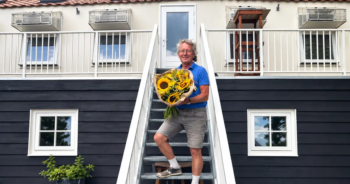 Home 7 Gert Koese holding a bouquet of yellow sunflowers on the staircase outside his pigeon loft in Sommelsdijk.